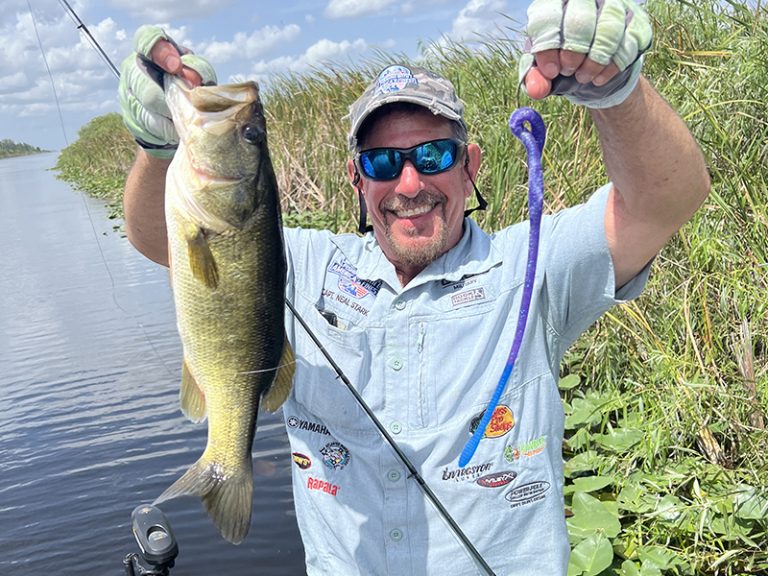 Florida bass angler holding a largemouth bass caught on a DeLong 16-inch Snake soft plastic lure