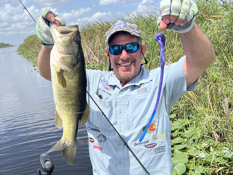 Florida bass angler holding a largemouth bass caught on a DeLong 16-inch Snake soft plastic lure