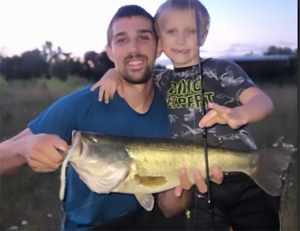 Father and son holding a big bass caught on a DeLong Lure, showing real fishing success and family outdoor moments